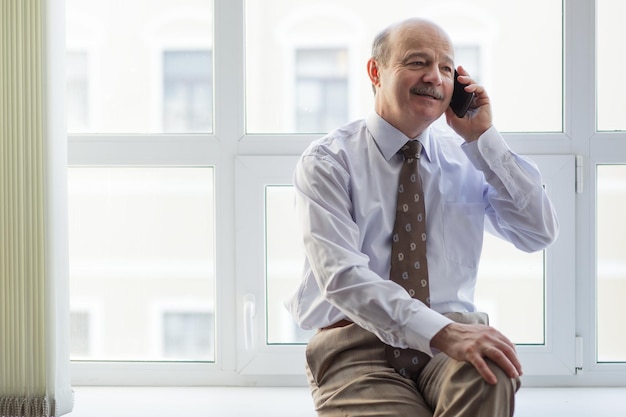 L'uomo d'affari anziano conduce colloqui informali al telefono