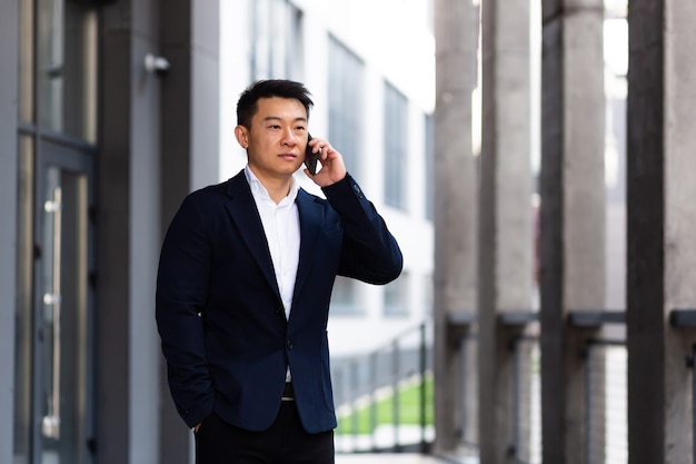 L'uomo d'affari asiatico che parla seriamente al telefono ha una conversazione arrabbiata