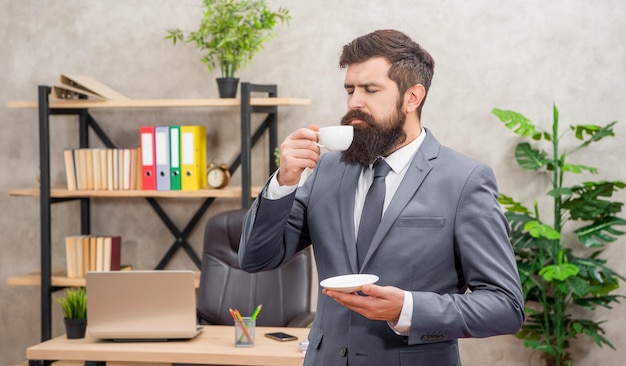 L'uomo d'affari barbuto si gode il caffè in ufficio con il ragazzo dello spazio di copia