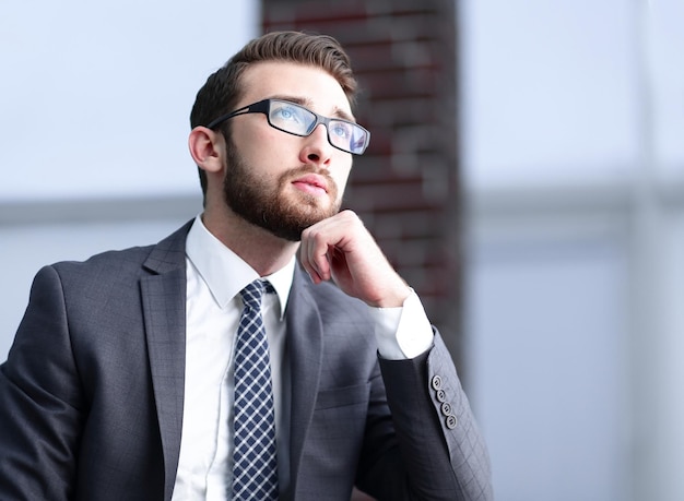 L'uomo d'affari bello pensa seduto sul divano nel suo ufficio