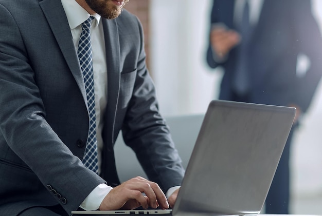 L'uomo d'affari bello sta lavorando con il computer portatile in ufficio