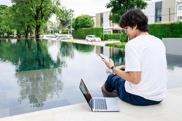 L'uomo d'affari bilancia lavoro e tempo libero in vacanza a bordo piscina con il computer portatile