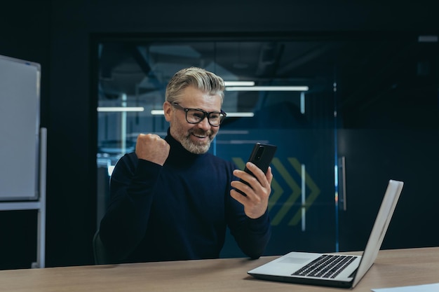 L'uomo d'affari che celebra la vittoria e il successo ha ricevuto buone notizie dall'uomo maturo dai capelli grigi all'interno dell'ufficio