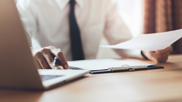 L&#39;uomo d&#39;affari che lavora all&#39;ufficio con firma un documento e un computer portatile. Concetto di business moderno.