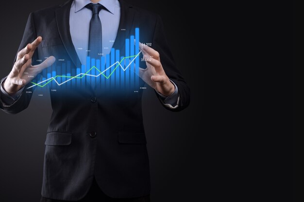 L'uomo d'affari che tiene grafici olografici e statistiche del mercato azionario guadagna profitti. Concetto di pianificazione della crescita e strategia aziendale. Visualizzazione di uno schermo digitale di buona qualità economica.