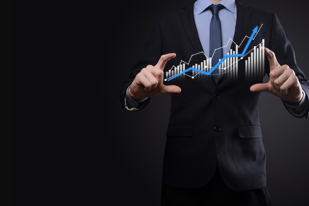 L'uomo d'affari che tiene grafici olografici e statistiche del mercato azionario guadagna profitti. Concetto di pianificazione della crescita e strategia aziendale. Visualizzazione di uno schermo digitale di buona qualità economica.