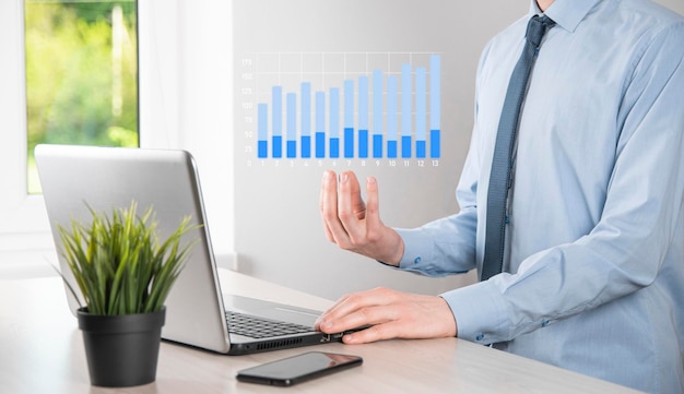 L'uomo d'affari che tiene tablet e mostra grafici olografici e statistiche del mercato azionario guadagna profitti. Concetto di pianificazione della crescita e strategia aziendale. Visualizzazione di una buona economia da schermo digitale.