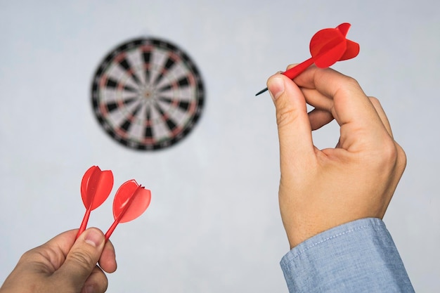 L'uomo d'affari che tiene un dardo che mira al target aziendale che punta il concetto di messa a fuoco ha colpito il bersaglio Successo negli affari