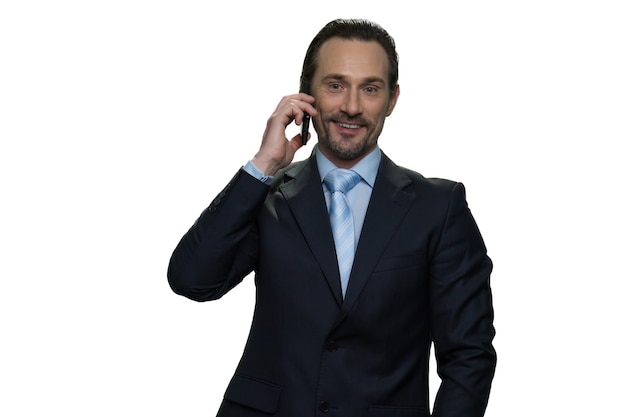 L'uomo d'affari di successo sta parlando al telefono. Maschio felice in un giubbotto isolato su muro bianco