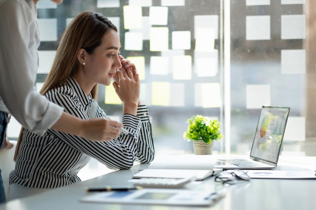 L'uomo d'affari e la donna d'affari discutono di lavorare con l'utilizzo di un computer portatile e di cercare informazioni sul grafico del mercato azionario per fare trading per realizzare un profitto Pianificazione e concetto di investimento