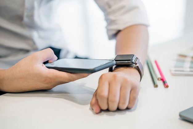 L&#39;uomo d&#39;affari facendo uso dello smartphone si collega a smartwatch