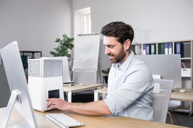 L'uomo d'affari felice lavora in ufficio su un piccolo deodorante e umidificatore portatile per condizionatore d'aria