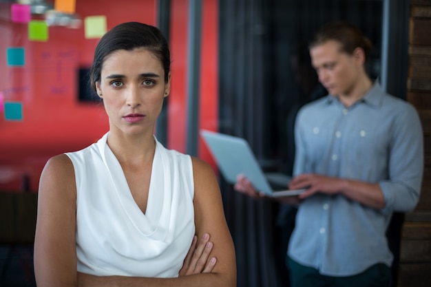 L'uomo d'affari femminile sicuro che sta con le armi ha attraversato in ufficio