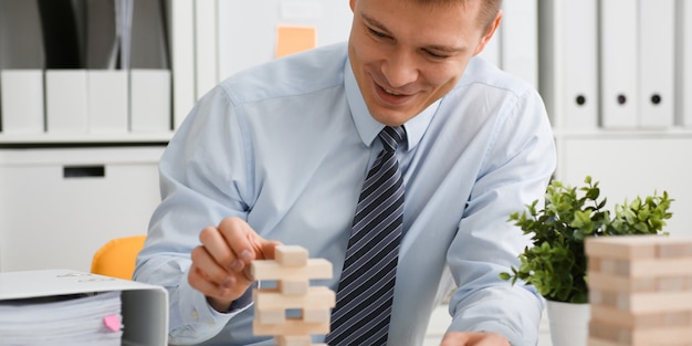 L'uomo d'affari gioca in una strategia della mano di jenga