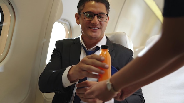 L'uomo d'affari ha succo d'arancia servito da una hostess in aereo. Concetto di viaggio viaggio d'affari.