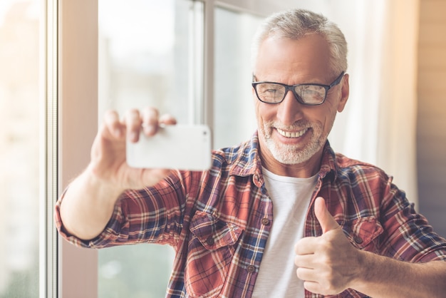 L'uomo d'affari in abbigliamento casual e occhiali sta facendo selfie