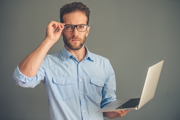 L'uomo d'affari in camicia e occhiali sta usando un computer portatile