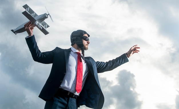 L'uomo d'affari in tuta e cappello da pilota lancia il giocattolo dell'aereo