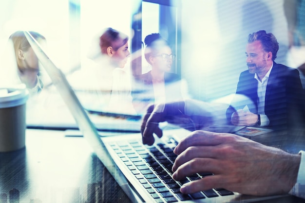 L'uomo d'affari lavora in ufficio con il laptop in primo piano Concetto di lavoro di squadra e partnership doppia esposizione