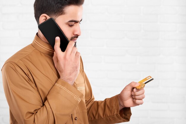 L'uomo d'affari mantiene la carta di credito e parla sul telefono cellulare