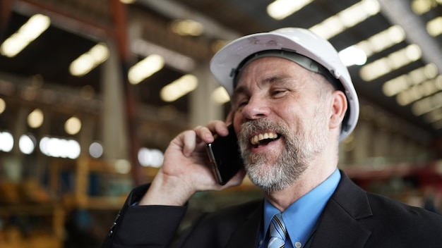 L'uomo d'affari nel magazzino della fabbrica sta parlando sul cellulare Industria della fabbrica Affari