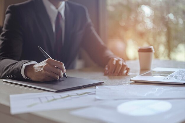 L'uomo d'affari seduto a lavorare alla scrivania dell'ufficio ha una tazza di caffè accanto per problemi e concetti di lavoro efficienti. uomo d'affari, lavoro, affari, tecnologia, gestione, concetti di pianificazione.