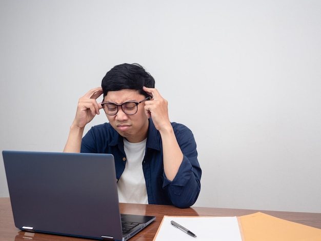 L'uomo d'affari seduto al tavolo di lavoro si sente provato e mal di testa per il duro lavoro