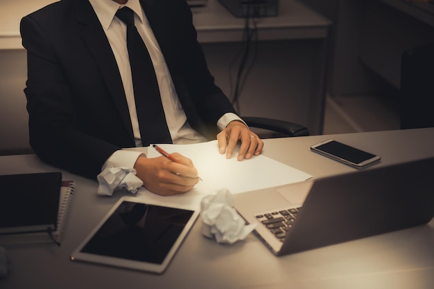 L'uomo d'affari seduto lavora sul bel ragazzo deskasian controlla il mercato azionario in smartphone mobile con laptop nel tono scuro officevintage