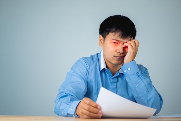 L'uomo d'affari si fa male agli occhi quando guarda la carta Si tocca l'occhio con le mani Concetto di oftalmologia Questo scatto è un ritratto medio ravvicinato