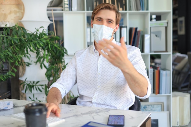 L'uomo d'affari sta lavorando in maschera medica preventiva in ufficio