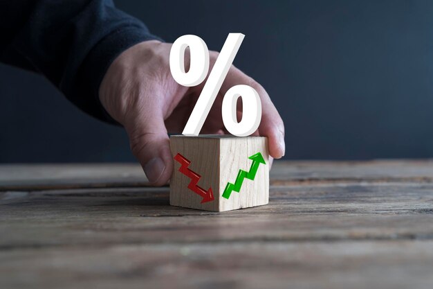 L'uomo d'affari tiene blocchi di legno con percentuale e freccia su o giù Tassi ipotecari e di prestito