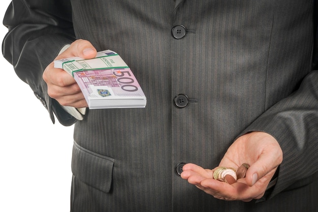 L'uomo d'affari tiene in una mano un pacco di soldi in euro e nell'altra una manciata di monete, primo piano, isolato su sfondo bianco