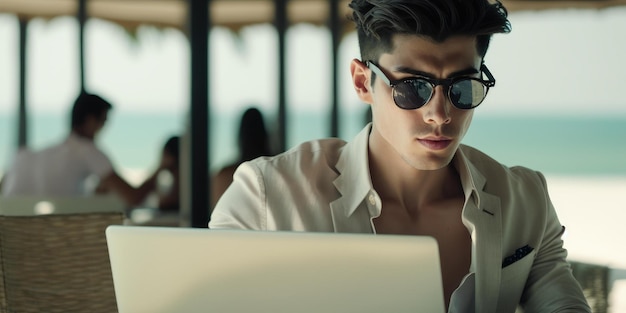 L'uomo d'affari usa il computer portatile nel beach club dell'hotel resort di lusso in estate