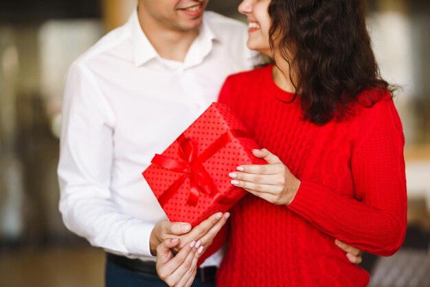 L'uomo dà alla sua donna una confezione regalo con nastro rosso Una coppia di innamorati che celebra il giorno di San Valentino