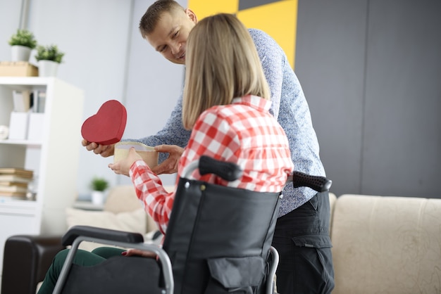 L'uomo dà un regalo alla donna in sedia a rotelle. Rapporto con il concetto di persona disabile