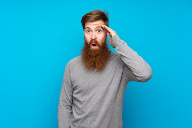 L'uomo dai capelli rossi con la barba lunga sull'azzurro isolato ha appena realizzato qualcosa e ha intenzione di risolverlo