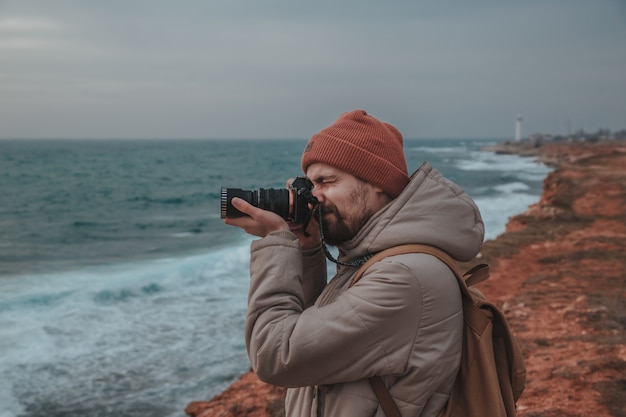 L'uomo dei pantaloni a vita bassa che guarda al faro in riva al mare