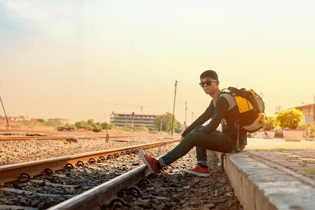 L&#39;uomo del viaggiatore che si siede e aspetta il treno sulla piattaforma ferroviaria