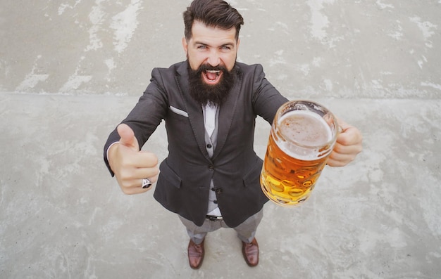 L'uomo della barba tiene la birra da un boccale di birra a tutta lunghezza emozioni di espressione grandangolare