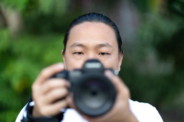 L'uomo della macchina fotografica professionale cinese tailandese asiatico pubblica e controlla l'immagine scattata