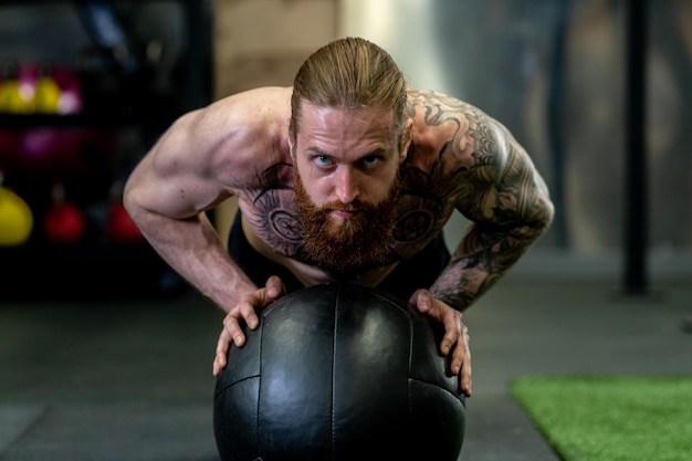 L'uomo della palla alza la barba spinge la medicina atletica spinge il concetto di fitness caucasico muscolare sexy dall'allenamento