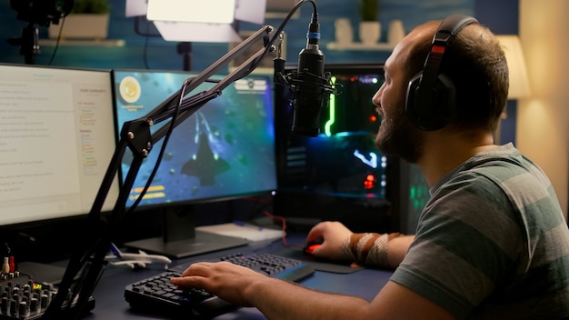 L'uomo dello streamer che indossa l'auricolare inizia a giocare ai videogiochi sparatutto spaziali online