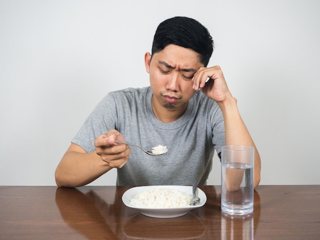 L'uomo depresso si sente annoiato dal cibo che piange non vuole mangiare il riso sul tavolo