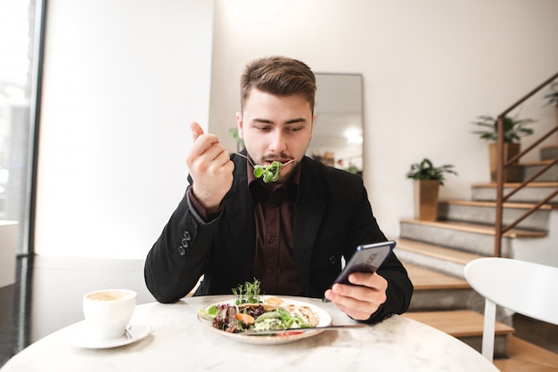 L'uomo di affari usa uno smartphone durante la prima colazione nel ristorante.