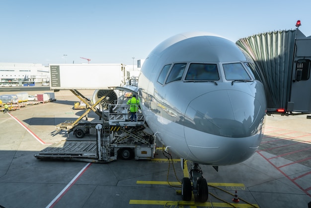 L&#39;uomo di carico sulla piattaforma di carico carica il trasporto aereo verso gli aerei cargo.