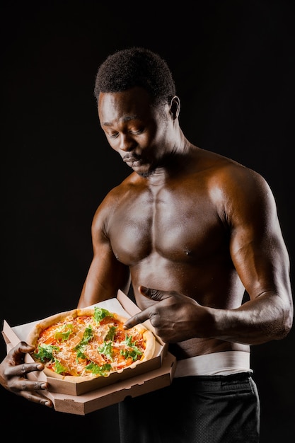 L'uomo di colore nudo sorpreso punta la pizza in una scatola di cartone