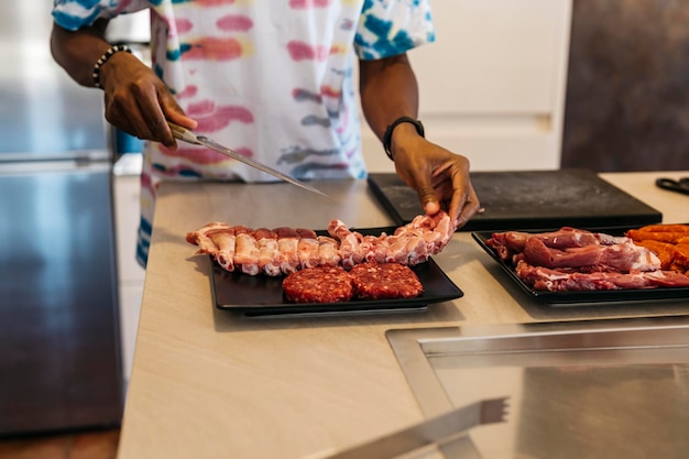 L'uomo di colore prepara vassoi di carne per un barbecue