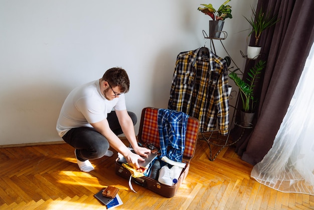 L'uomo di concetto di viaggio ha messo le cose nella borsa sovraccaricata della valigia con i vestiti