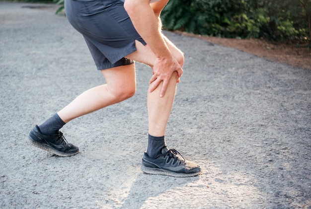 L'uomo di fitness sportivo soffre di dolore al ginocchio durante la corsa o il jogging