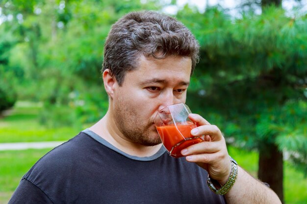 L&#39;uomo di mezza età beve succo di pomodoro per strada